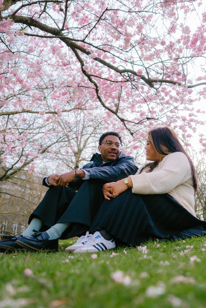 Couple sitting in grass under blossom