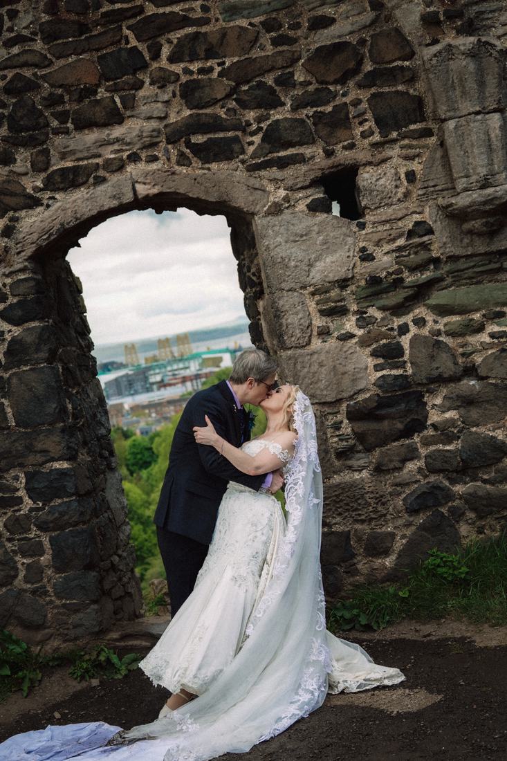 Couple kissing inside a ruined stone arch on Arthur's Seat