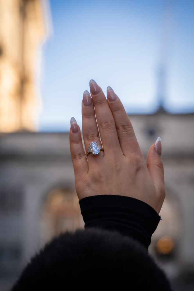 Hand showing an engagement ring against the sky