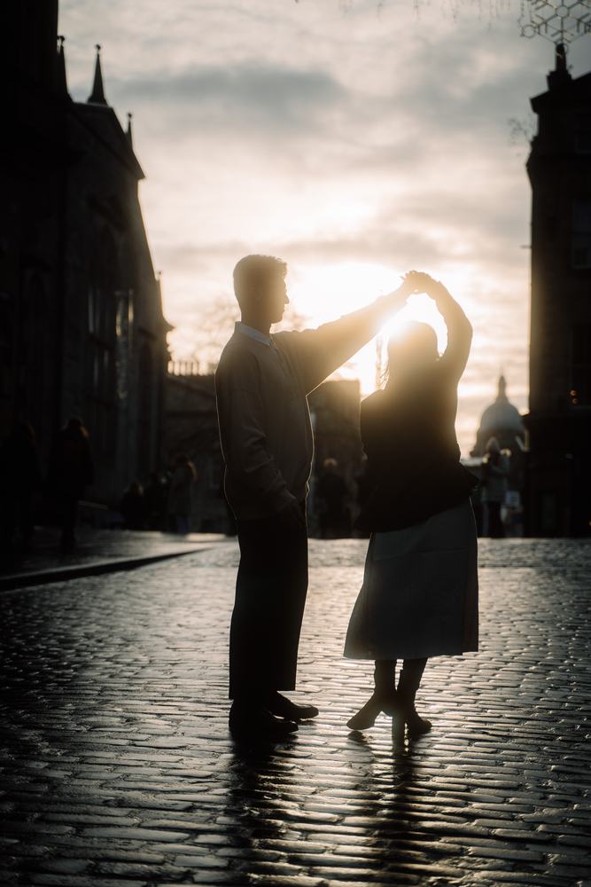 Couple dancing in silhouette on wet cobbles