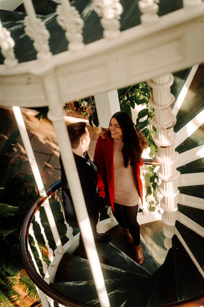 Couple on a white spiral staircase in a glasshouse