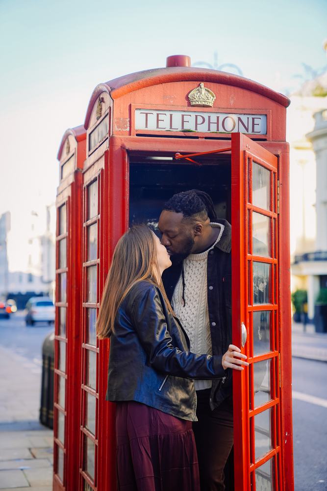 Couple kissing inside a red phone box