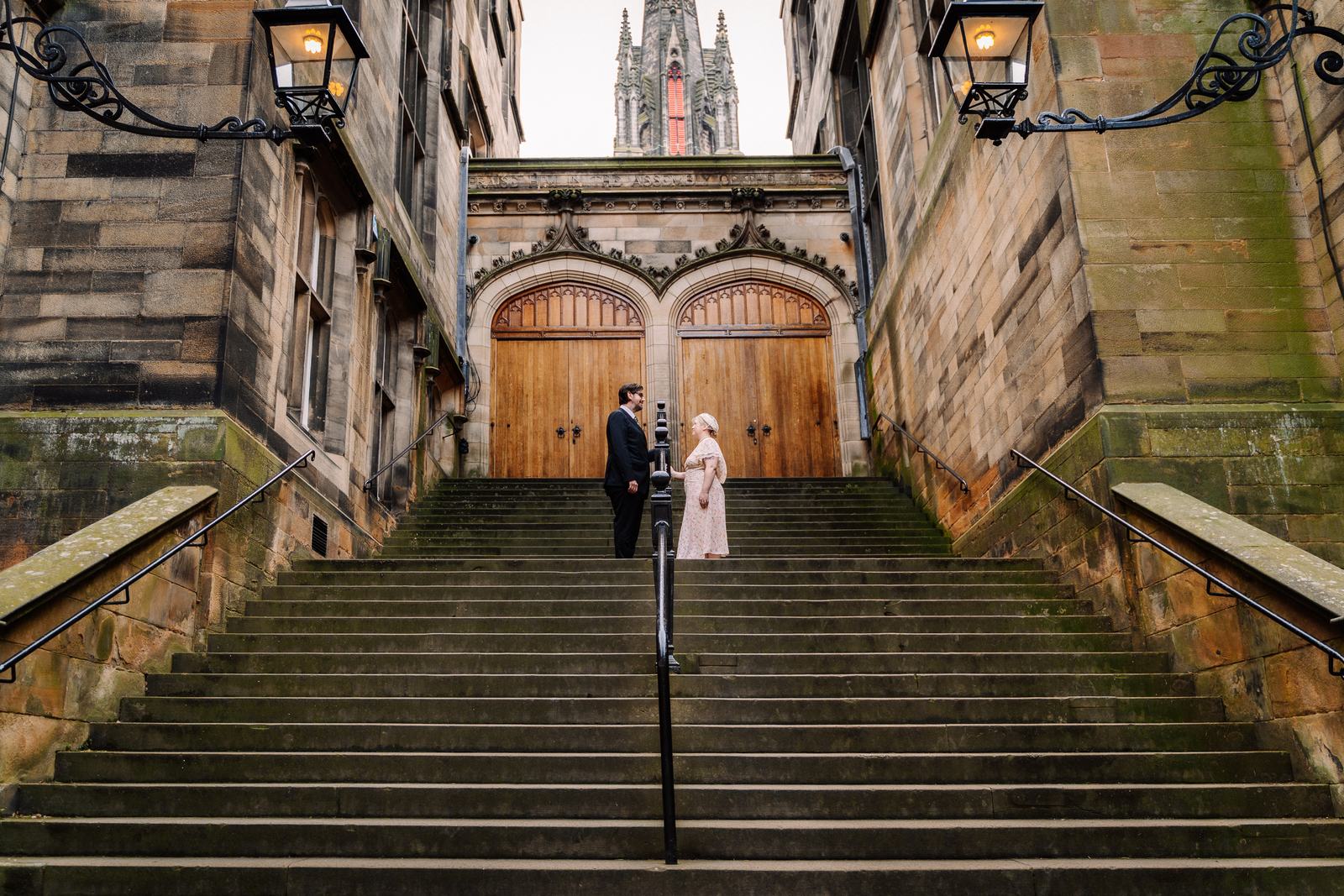 Newlyweds on grand stone steps in Edinburgh Old Town
