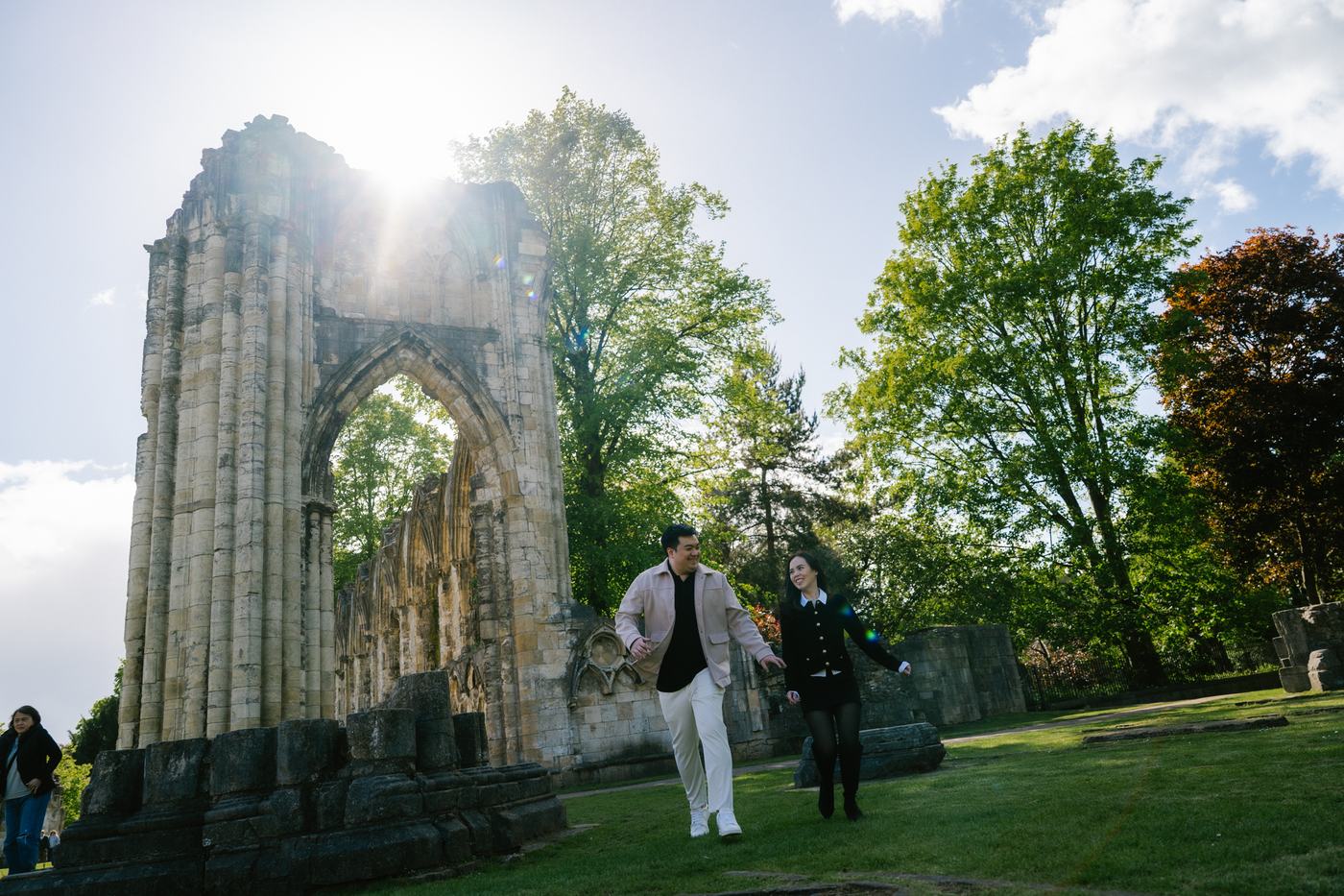 Couple walking past a ruined abbey arch in York